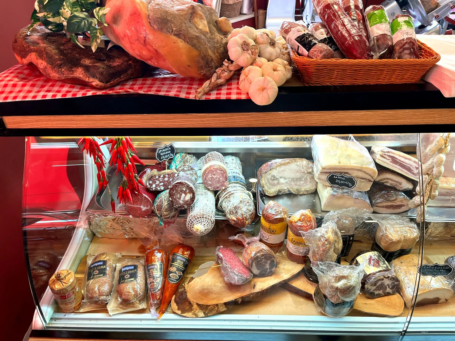 Cured meats counter at Origini Salumeria with hanging prosciutto and Italian salami