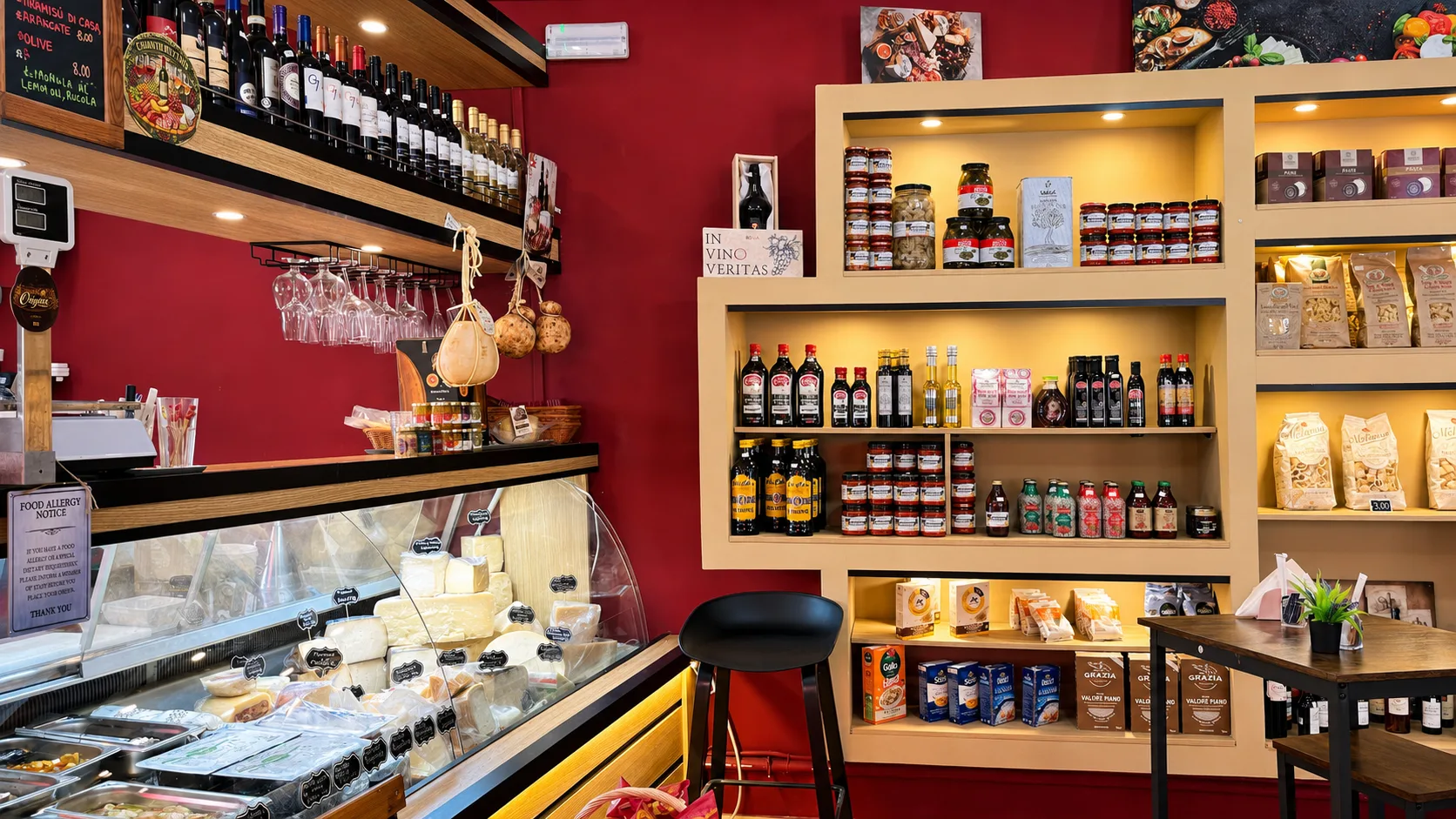 Inside Origini Salumeria in Swieqi: shelves of Italian products, cheese counter and Italian wine on burgundy walls